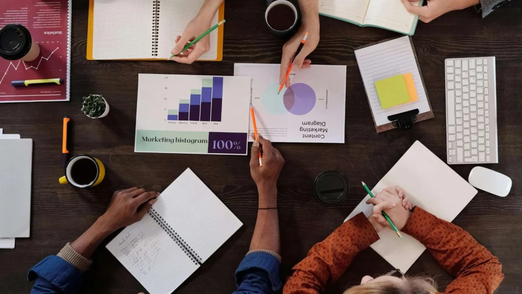 People having a discussion using graphs and metrics using a pencil and a notebook for taking notes