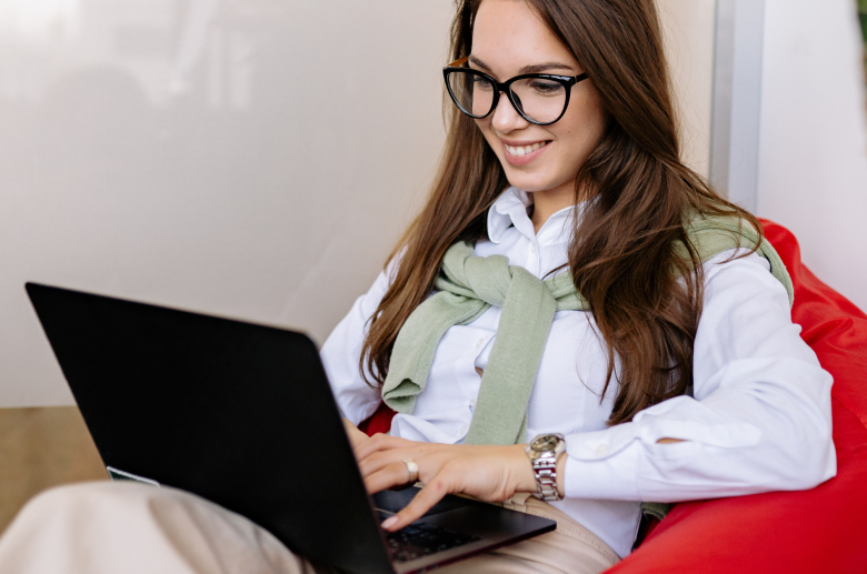 Woman in glasses working on a laptop in a red chair