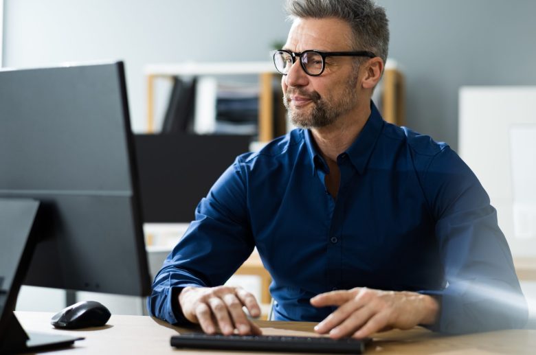 Man in glasses typing at a desktop computer