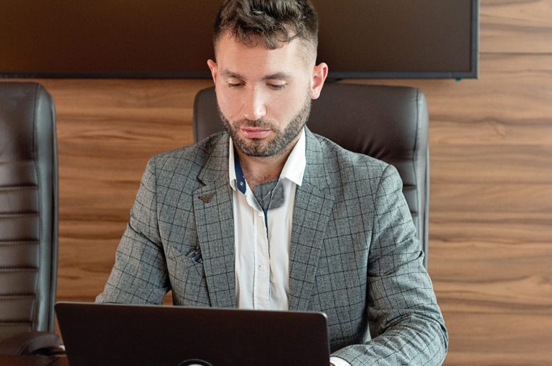Man in a blazer working on a laptop at a desk