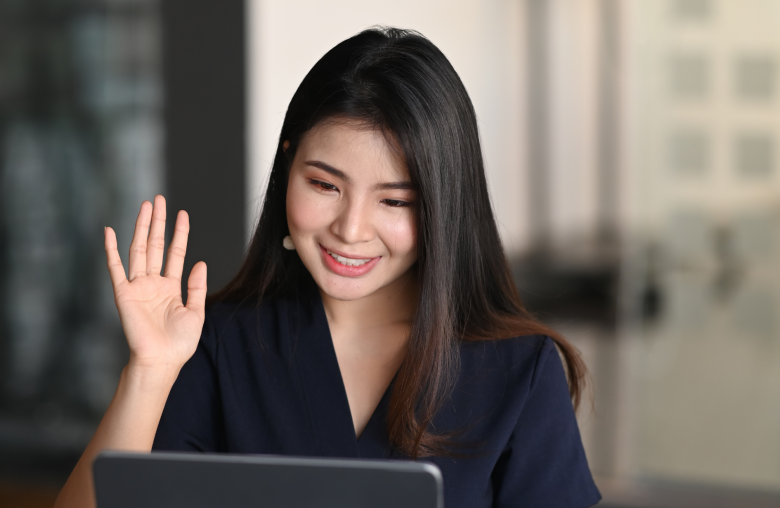 Smiling woman waving at her laptop