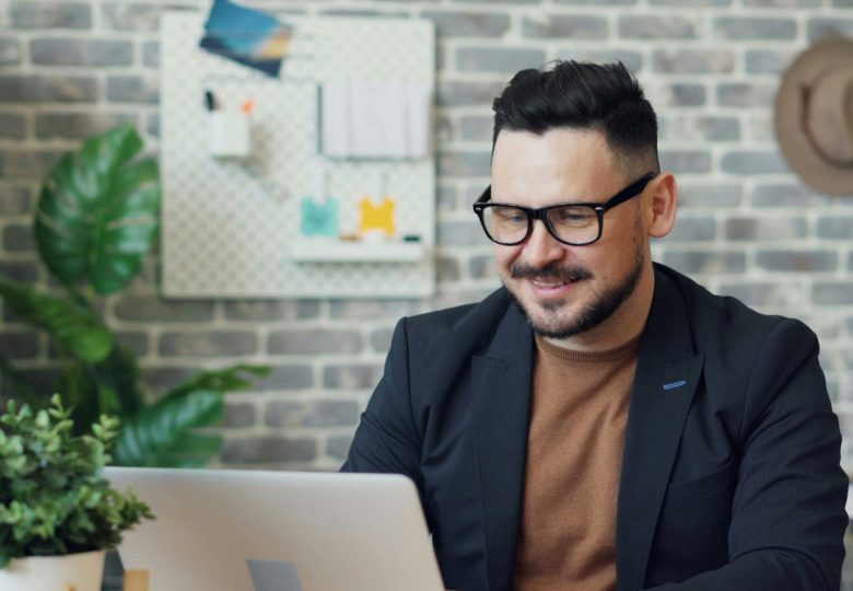 Smiling man in glasses working on a laptop