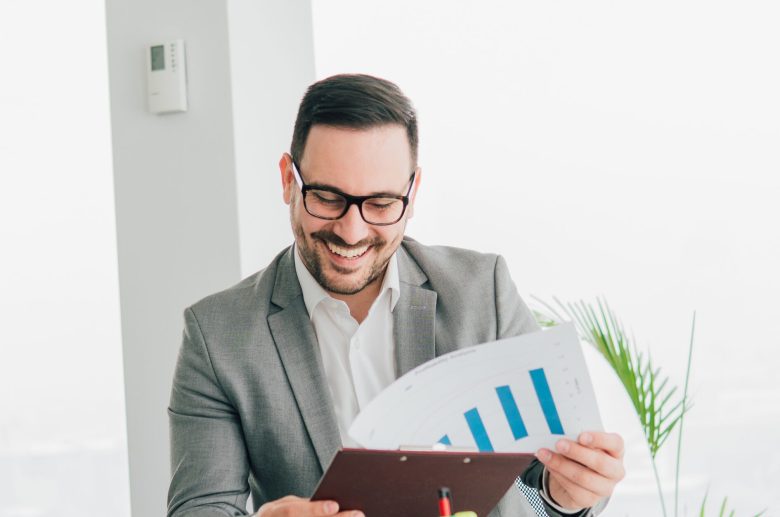 Smiling man in glasses holding a clipboard with a chart