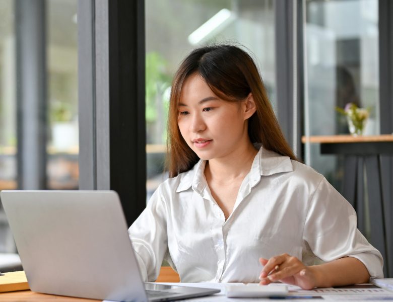 Woman taking notes beside a laptop