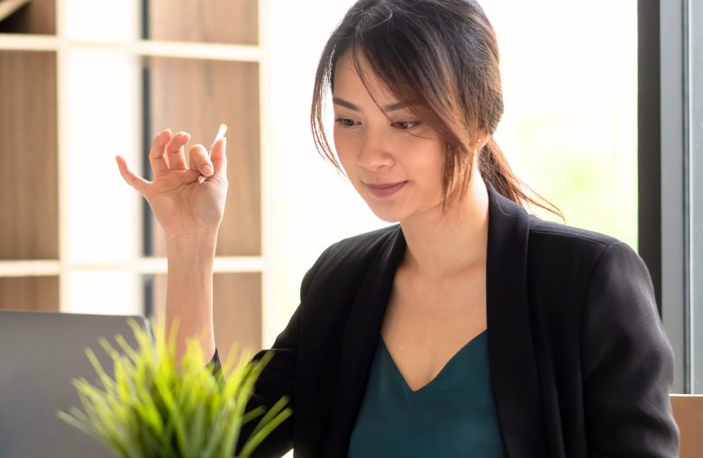 Woman in a blazer gesturing while reading at her desk