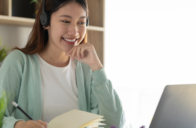 Smiling woman wearing a headset writing in a notebook