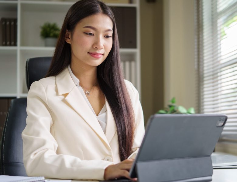 Woman in a blazer working on a tablet at her desk