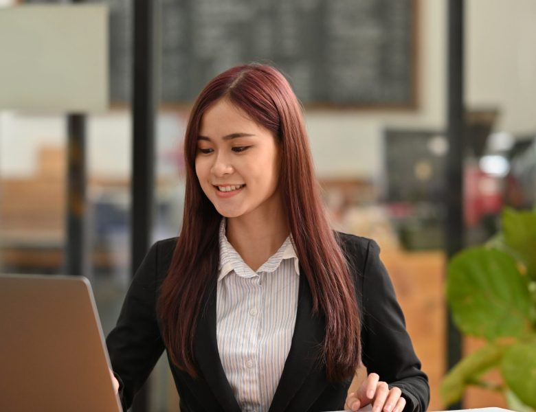 Smiling woman in a blazer working on a laptop