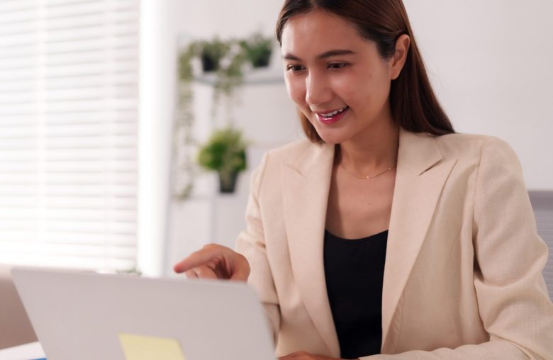 Smiling woman in a blazer working on a laptop