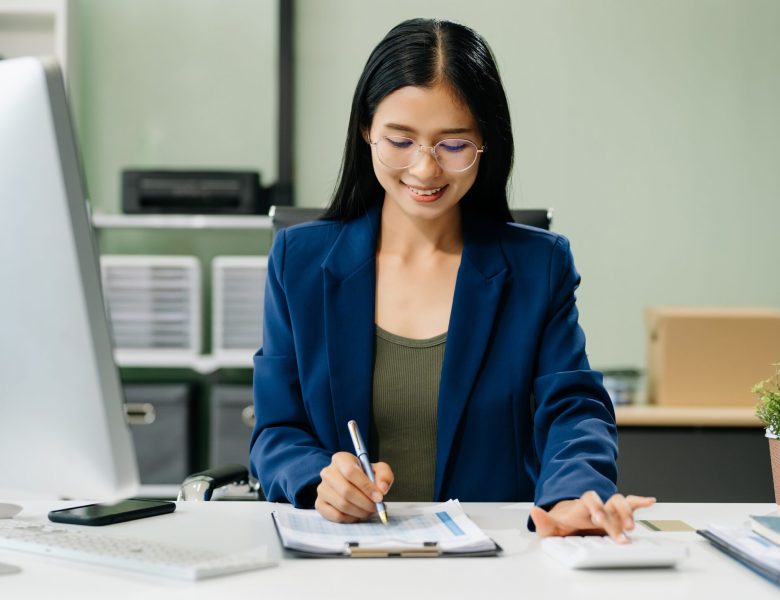 Woman in a blazer writing notes at her desk