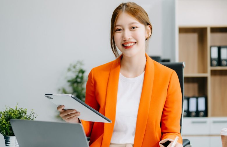 Smiling woman in an orange blazer holding a clipboard
