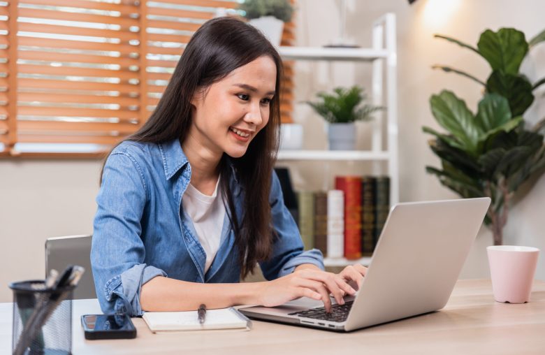 Woman typing on a laptop at a home desk