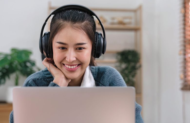 Smiling woman wearing headphones at a laptop