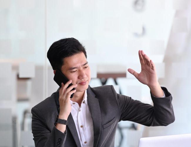 Man in a suit talking on the phone and raising his hand