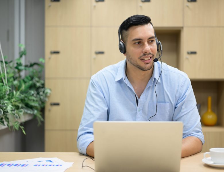 Man wearing a headset working on a laptop