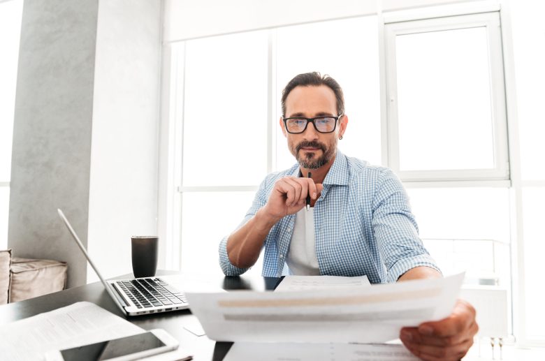 Man in glasses reading documents at a desk