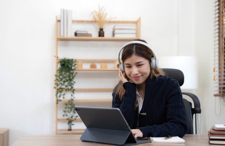 Woman wearing headphones working on a tablet at home