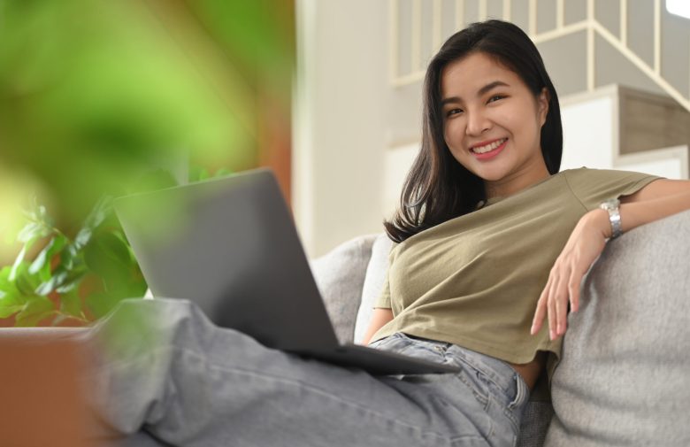 Smiling woman relaxing on a sofa with a laptop