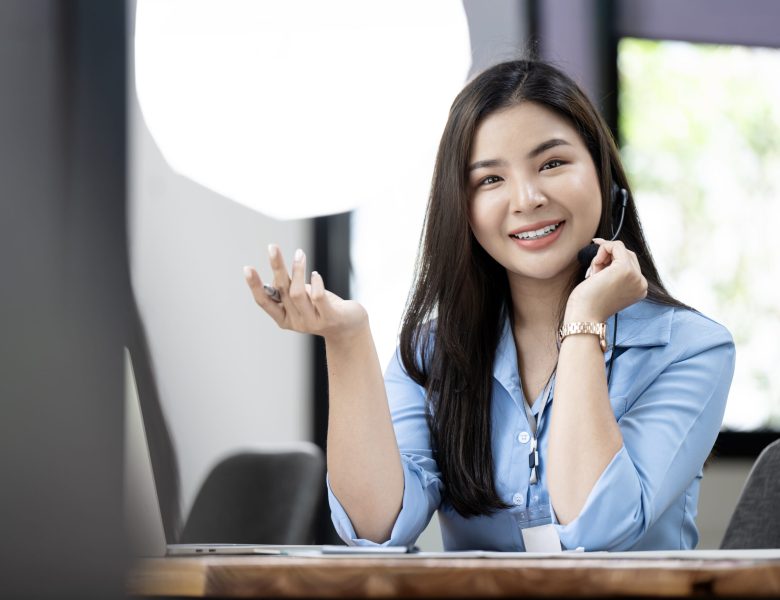 Smiling woman wearing a headset talking at her desk