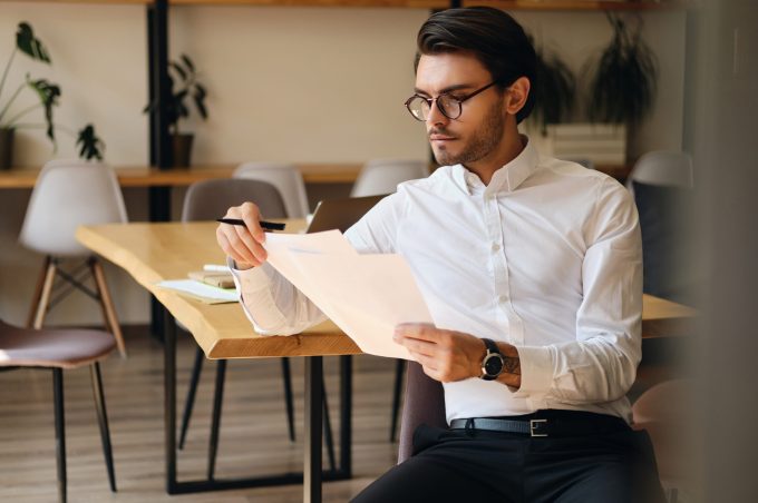 Man in glasses reading a document at a table