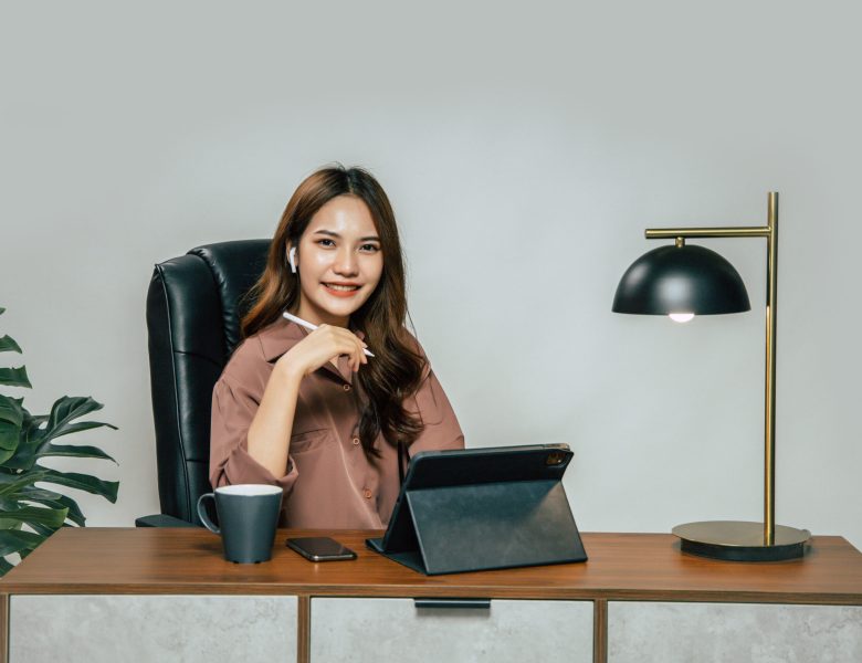 Smiling woman sitting at a desk with a tablet